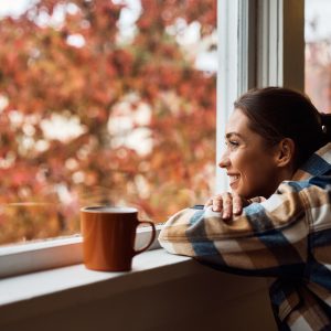 Young happy woman enjoying the view from her apartment window. Copy space.
